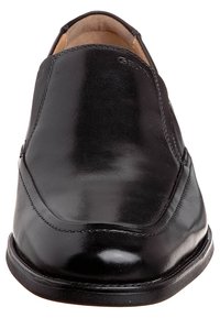 Black leather loafers with a smooth finish, rounded toe, and minimalistic design. Features a slight heel and stitched detailing along the sides.