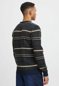 Tumesinise kudumisega sviiter, millel on geomeetrilised mustrid pruunis ja kreemis, ümar kaelus ning ribadega mansetid ja allserv. Tekstuuriga kangas.