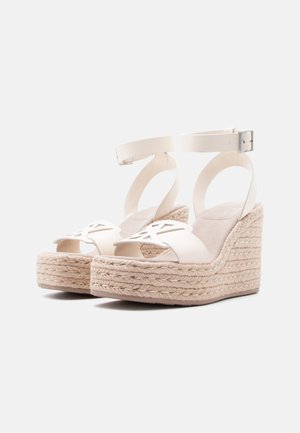 Μπεζ πλατφόρμας με σφήνα και πλεκτή σκοινί, ανοιχτό δάχτυλο, σχέδιο με κοψίματα στο μπροστινό λουρί και λουρί στο αστράγαλο με ασημένια αγκράφα.