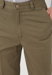 Pantalones caqui de algodón con una textura suave, que cuentan con cierre de botón y bolsillos laterales, ajuste entallado y detalles de costura sutiles.