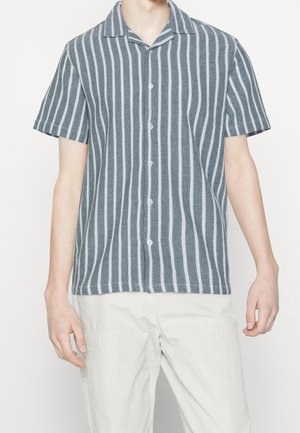 Camicetta a maniche corte a righe in teal e bianco, con colletto, chiusura a bottoni, tessuto strutturato e righe verticali.