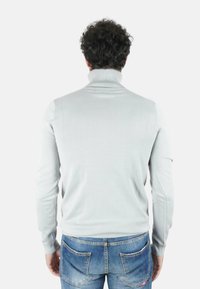Maglione a collo alto grigio in morbido tessuto a maglia, con maniche lunghe e collo a coste, abbinato a jeans blu casual.
