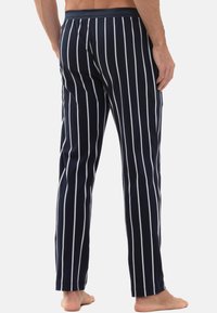 Marineblauwe pyjamabroek met verticale witte strepen, gemaakt van zachte stof, voorzien van een elastische tailleband en een recht model.