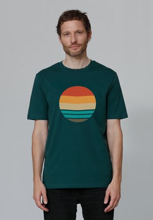 Dark green cotton t-shirt featuring a circular graphic with horizontal stripes in orange, yellow, and teal, centered on the chest.