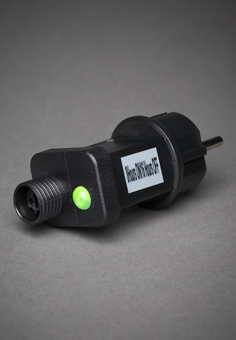 Schwarzer Elektrostecker-Adapter mit grünem Anzeigelicht und einem Etikett, das "8 Stunden EIN/16 Stunden AUS" lautet, auf einer grauen Oberfläche.