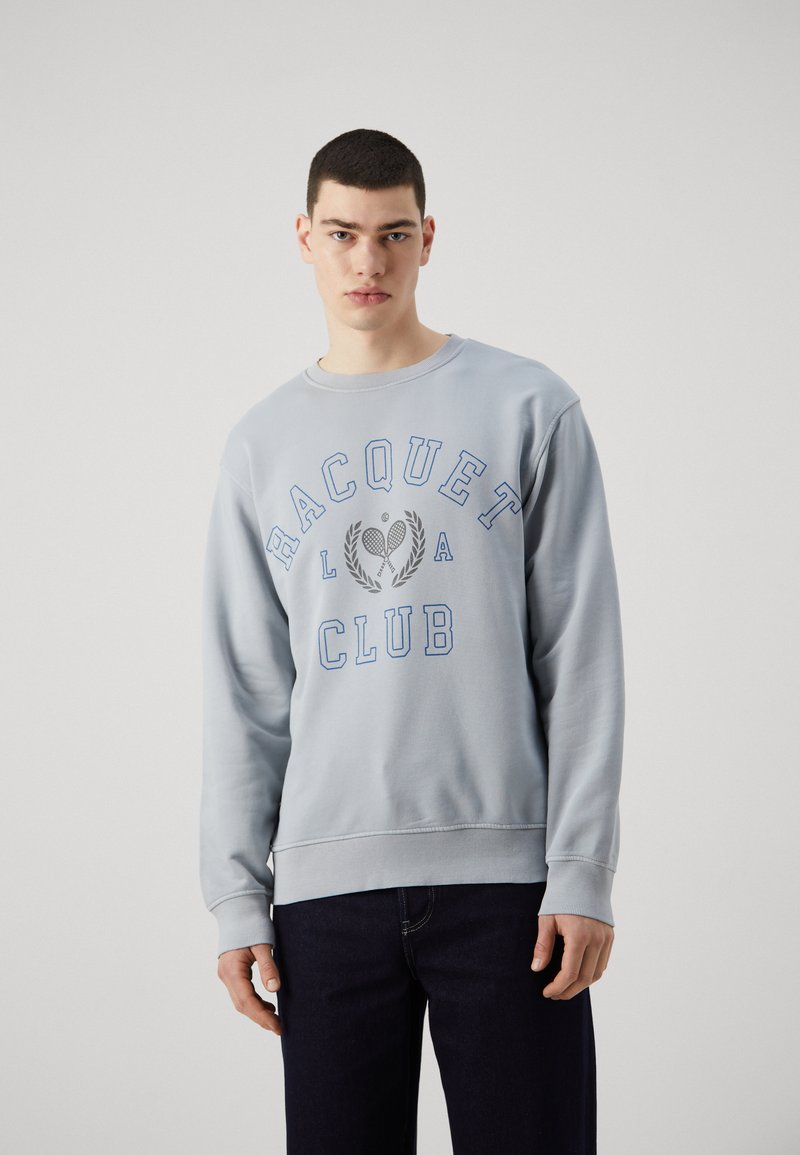 Sudadera azul claro de manga larga, con puños acanalados y cuello redondo. Presenta un estampado gráfico "RACQUET CLUB" y un motivo de tenis en azul.