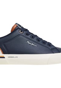 Zapatilla deportiva azul marino con parte superior de cuero suave, suela de goma color crema, detalles en marrón, ojales de metal y un logotipo en relieve en el lateral.