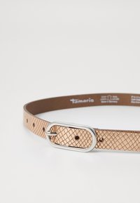 Ceinture en cuir texturé rose gold avec une boucle ovale en argent lisse, comportant des trous également espacés le long de la sangle pour un ajustement de taille.