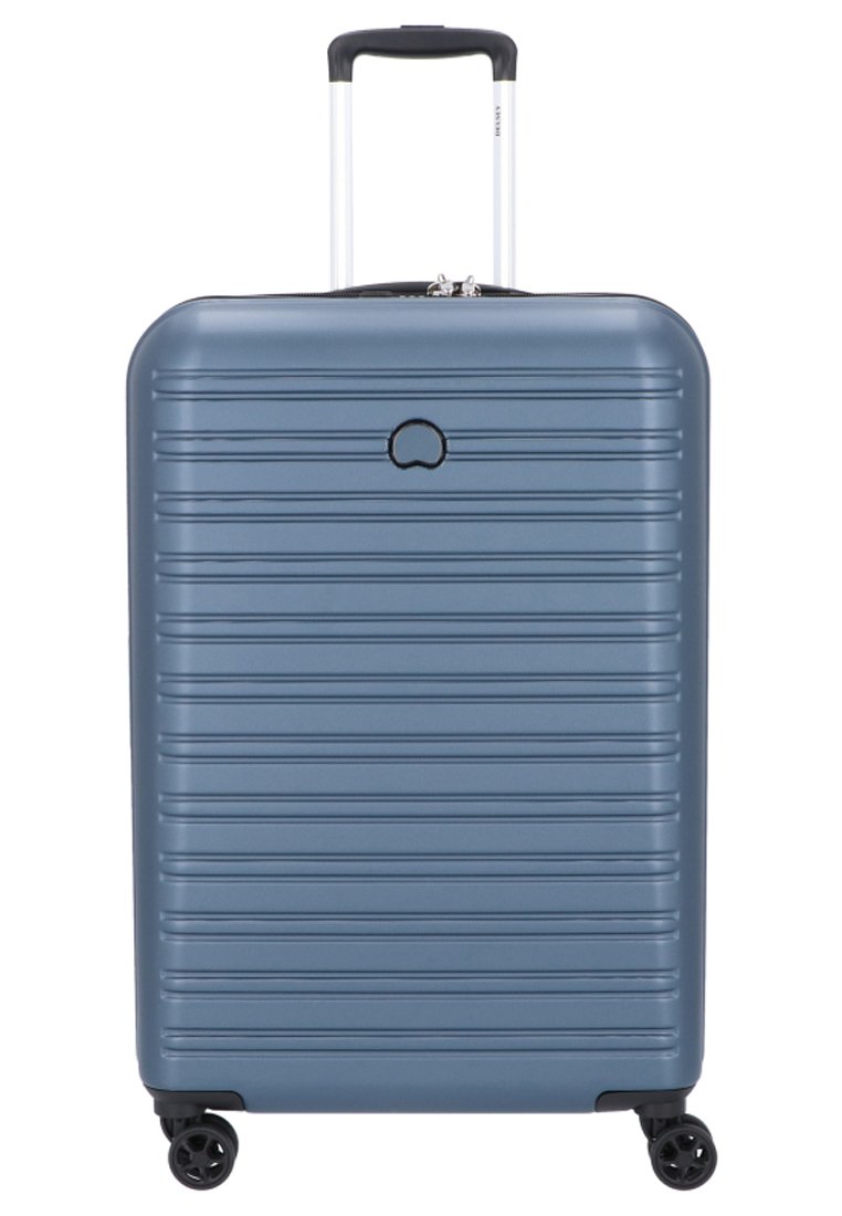 Valigia rigida di colore blu metallico con scanalature verticali, maniglia estensibile e quattro ruote girevoli a 360 gradi per una facile mobilità.