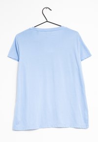 Ljusblå T-shirt i mjukt tyg, kort ärm, rundad halsringning och rak fåll. Hänger på en svart metallklädhängare mot en vit bakgrund.