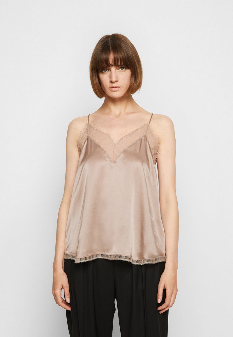 Satin camisole vaaleenharmaana, jossa on pitsiyksityiskohtia kaula-aukossa ja helmassa. Ohuet olkaimet ja A-linjainen malli, yhdistettynä tummiin, löysiin housuihin.