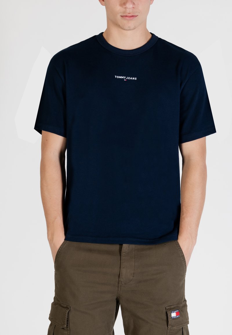 T-shirt in cotone blu navy con scollo rotondo e maniche corte. Presenta un piccolo logo bianco "TOMMY JEANS" sul petto.