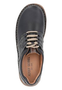 Zapato de cuero negro con acentos de costura, puntera redonda y cordones beige. Presenta una suela similar al corcho y un logo grabado en el interior.