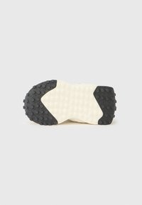 Λαστιχένια σόλα παπουτσιού με υφή σε μαύρο χρώμα και κυκλικά αντιολισθητικά, που αντιπαραβάλλεται με το πιο ανοιχτό και λείο κεντρικό τμήμα.