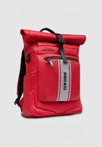 Mochila roja con tapa enrollable hecha de material cauchozado, con un bolsillo frontal con cremallera, correas negras y una franja gris con la marca "DUCATI".