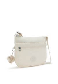 Beige crossover taske med lynlås frontlomme, justerbar rem og pelsagtig dyreformet charms vedhæftet. Glat, holdbart materiale.
