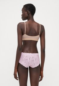 Light brown bralette with adjustable straps paired with pink lace shorts featuring floral patterns and a scalloped hem.