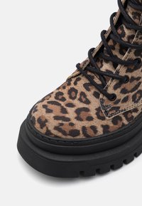 Ankelstøvler med leopardmønster lavet af tekstureret suede med sorte snørebånd, der har en kraftig sort gummisål og textured design.