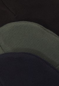 Collection of three knitted beanies: black, dark green, and navy. Each features a soft texture and rounded shape with visible stitching.