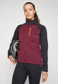 Volledige zip fietsjack in kastanjebruin en zwart met een oranje ritszak, met een aansluitende pasvorm en zachte, rekbare stof.