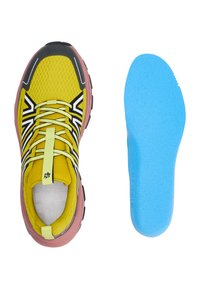 Chaussure de sport avec une tige en mesh jaune, des accents noirs et blancs, et une semelle rose. Comprend une semelle intérieure bleue avec une surface texturée.