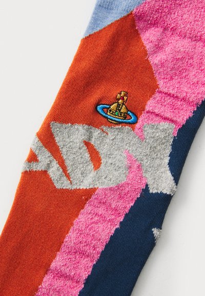 Stricksocke mit orangefarbenen, pinken, blauen und navy-segmentierten Abschnitten, grauen "ADY"-Buchstaben und einem gestickten Design einer Glocke in einem Ring.
