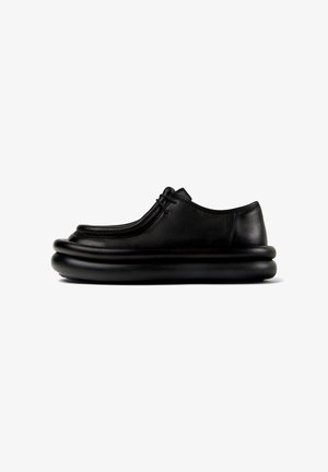 Černá kožená bota s kulatou, polstrovanou podrážkou, elegantním designem a minimem švů. Disponuje nízkým profilem a šněrováním.