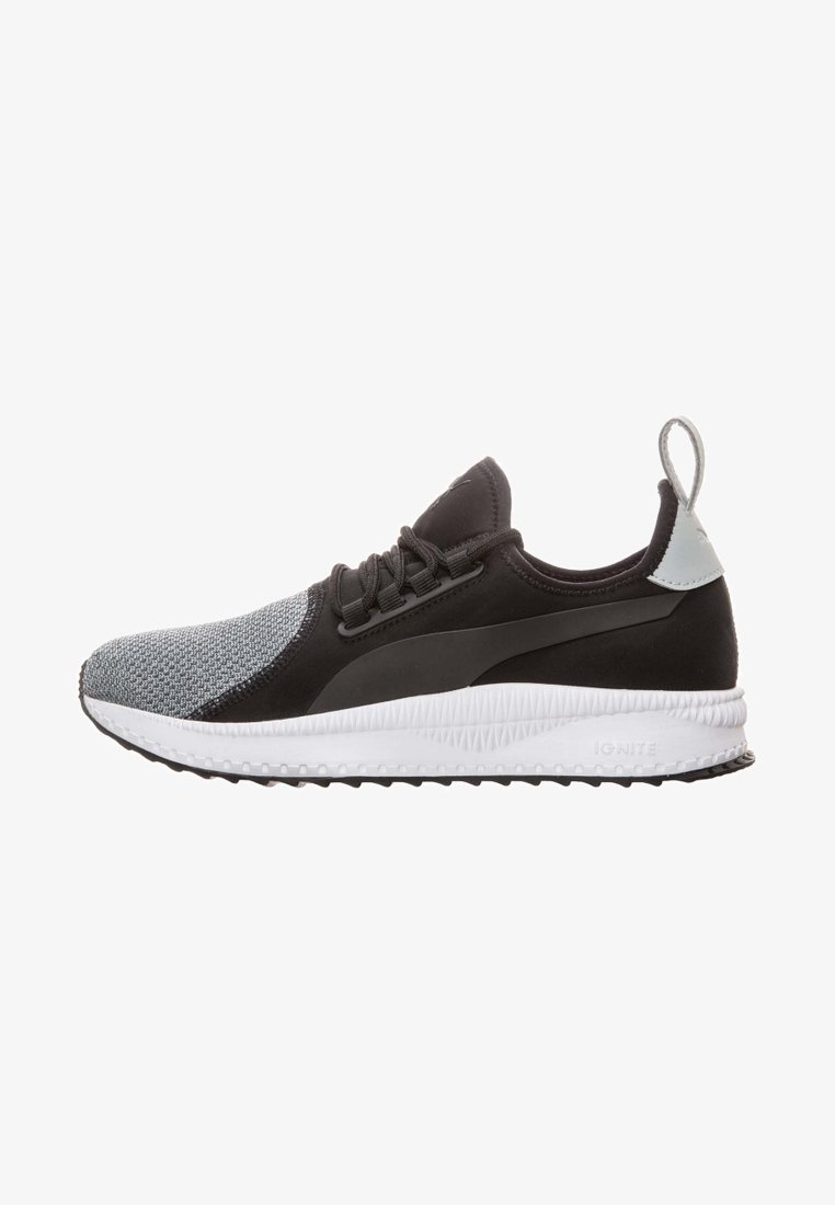 Vue latérale d'une chaussure de sport noire et grise avec une semelle blanche et un onglet à l'arrière, présentant un avant en maille et un design à lacets.