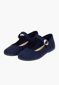Zapatillas de lona azul marino con suela plana, punta redondeada y correas ajustables con detalle de hebilla plateada.