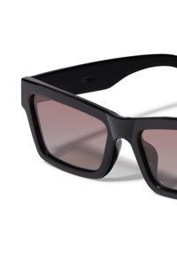 Ochelari de soare negri cu rame dreptunghiulare supradimensionate, lentile nuanțate brune cu gradient și finisaj lucios. Remarcabili pentru brațele groase și designul unghiular.