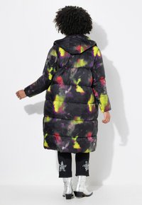 Cappotto imbottito nero con design astratto multicolore, cappuccio e maniche lunghe. Taglio alla vita con una texture liscia e riflessi lucidi.