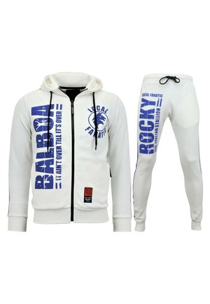 Witte hoodie met ritssluiting, voorzien van blauwe grafische tekst en logo, gecombineerd met bijpassende broeken met zijstrepen en vergelijkbare ontwerpen. Gemaakt van een katoenmix.