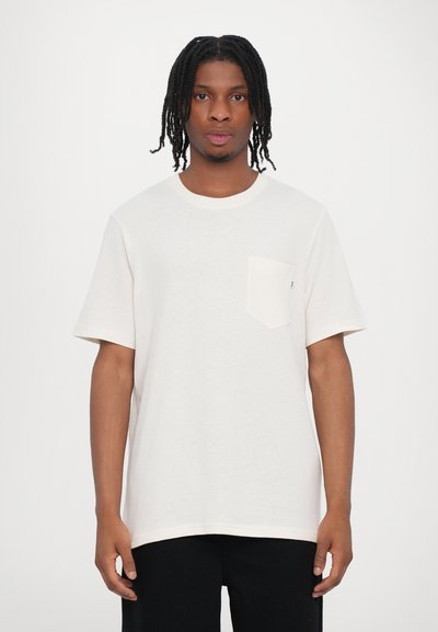 Camiseta de algodón blanca de mangas cortas, con cuello redondo y un único bolsillo en el lado izquierdo del pecho; textura suave y corte relajado.