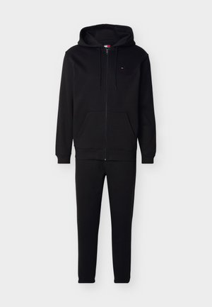 Must kaheosaline dressipluus lukuga ja ees taskutega ning nööridega kapuuts, mida kannavad sobivad kitsad püksid.