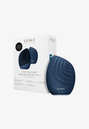 Donkerblauwe traanvormige sonische gezichtsborstel met een gestructureerd oppervlak, getoond naast de witte doos met het label "GESKE SmartAppGuided 5 in 1."