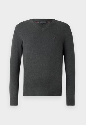 Šedý pletený svetr s výstřihem do V, dlouhými rukávy, žebrovanými manžetami a lemem. Na hrudi se nachází malé logo v červené, bílé a modré barvě.