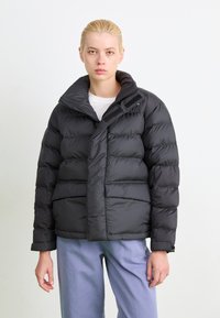 Schwarzedaunenjacke mit übergroßem Kragen, Reißverschluss und zwei Fronttaschen. Glatte Textur mit gesteppten Details und verstellbaren Bündchen.
