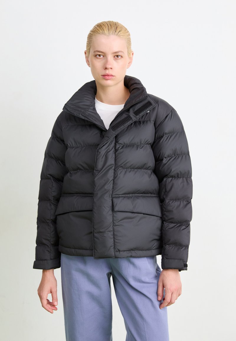 Schwarzedaunenjacke mit übergroßem Kragen, Reißverschluss und zwei Fronttaschen. Glatte Textur mit gesteppten Details und verstellbaren Bündchen.