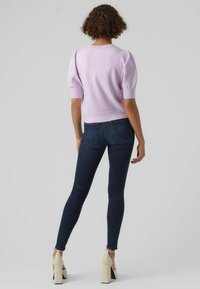 Lilla strikket genser med pufferm, kombinert med mørke skinny jeans og kremfargede blokkheler. Enkel, tettsittende design.