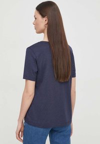 T-shirt in cotone blu navy con maniche corte, vestibilità rilassata e scollo rotondo, mostrato da dietro con capelli lisci.