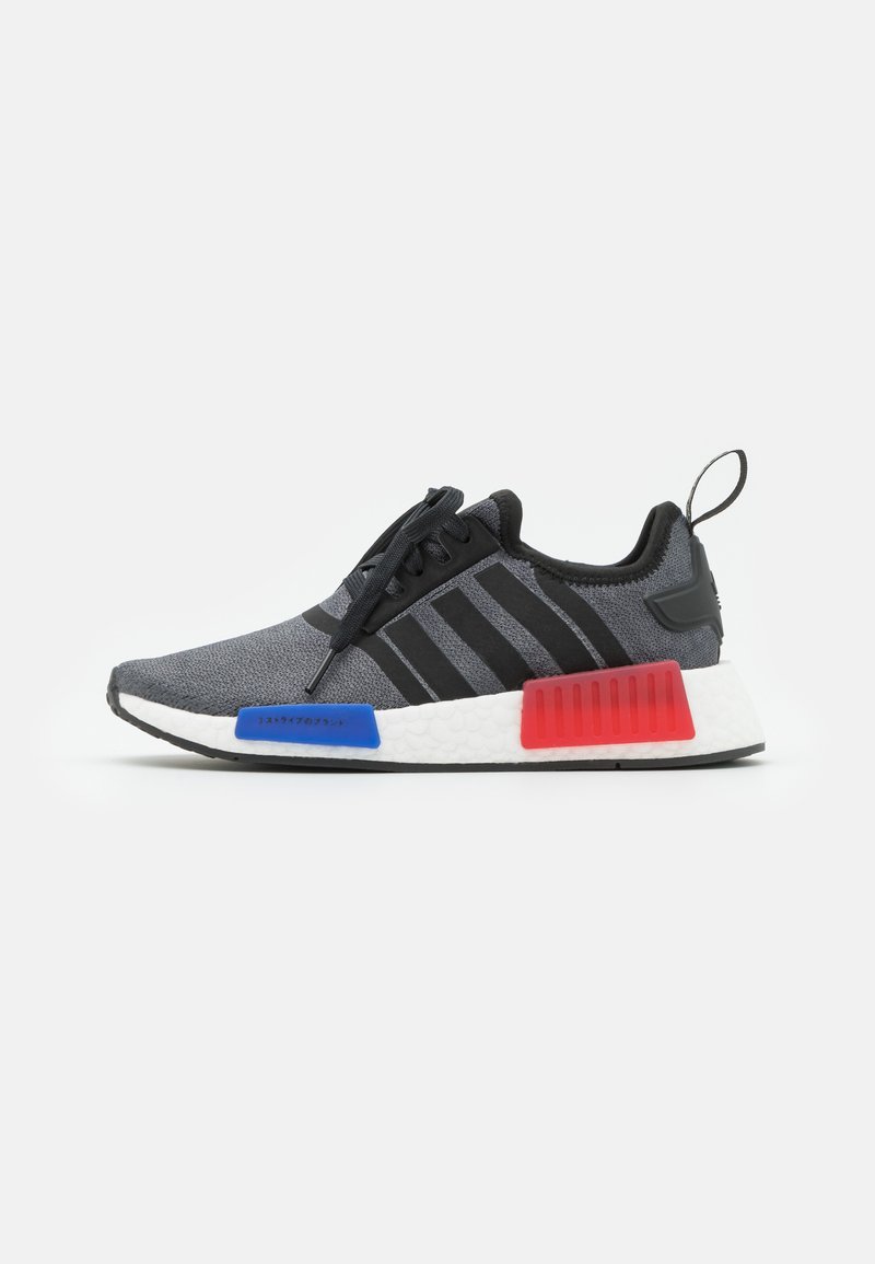 Black and gray athletic sneakers with a textured upper, three black stripes, blue and red accents on the sole, and a reinforced heel tab.