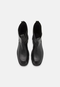 Black leather ankle boots with elastic side panels, rounded toe, and textured outsoles. Minimalist design, smooth surface.