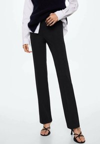 Black straight-leg trousers made from smooth fabric, featuring a mid-rise waistband. Styled with a white shirt and dark knitted vest.