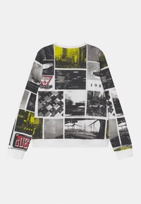 Sudadera colorida con un collage de fotografías en blanco y negro con acentos amarillos. El material parece suave; puños y cuello acanalados.