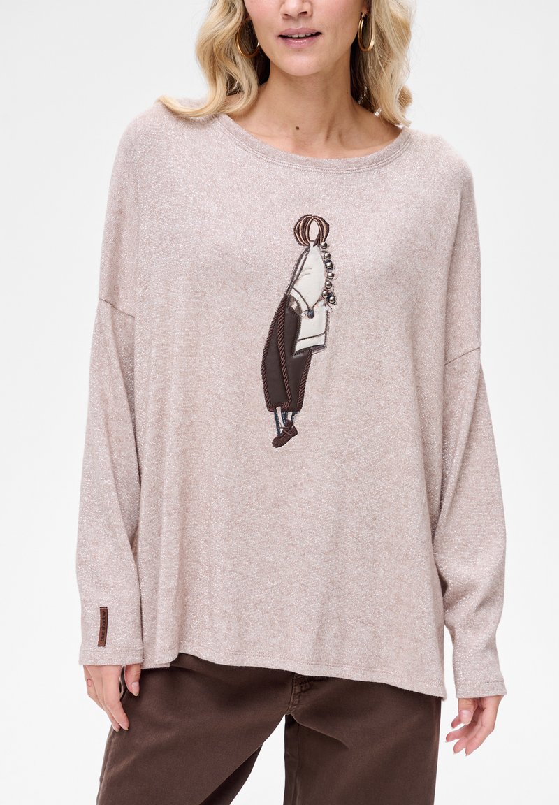 Jasnoróżowa bluzka z długim rękawem z haftowanym wzorem postaci w kolorze brązowym. Miękka w dotyku, o luźnym kroju; posiada małą metkę z logo na rękawie.
