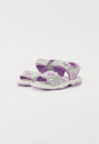 Silberne und lila Sandalen mit strukturierter Oberfläche, ausgestattet mit Klettverschlüssen und Herz-/Stern-Akzenten. Gemusterte Einlegesohlen und flexible Sohlen.