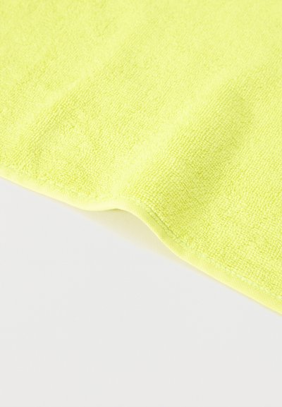 Chiffon en microfibre jaune vif avec une surface douce et texturée, étalé à plat avec un léger pli visible sur un fond blanc.