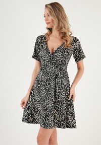 Leopard print wrap dress in black and beige. Short sleeves, v-neckline, and a tie at the waist. Flowing skirt with a flared hem.