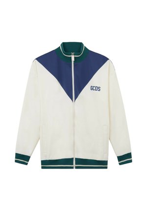 Giacca bianca con zip, con chevron blu sul petto, collo, polsini e orlo a coste verdi, e logo "GCDS" sul lato sinistro.