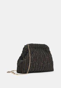 Sort stofhåndtaske med tekstureret, bølget mønster, pyntet med perler. Har en guldkæde-rem og lynlås for sikker adgang.